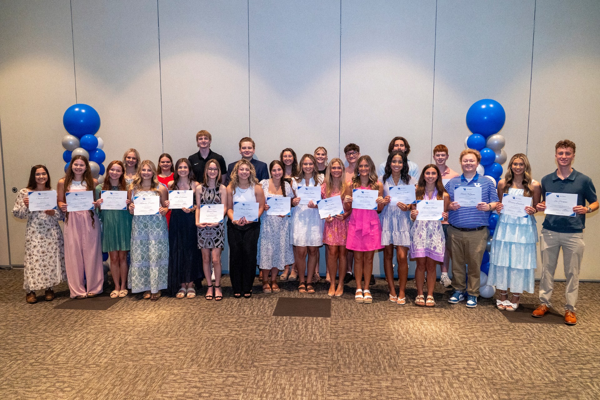 A group of teens holding certificates pose for a group photo.