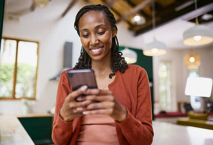 A woman smiles as she reads something on her smartphone.